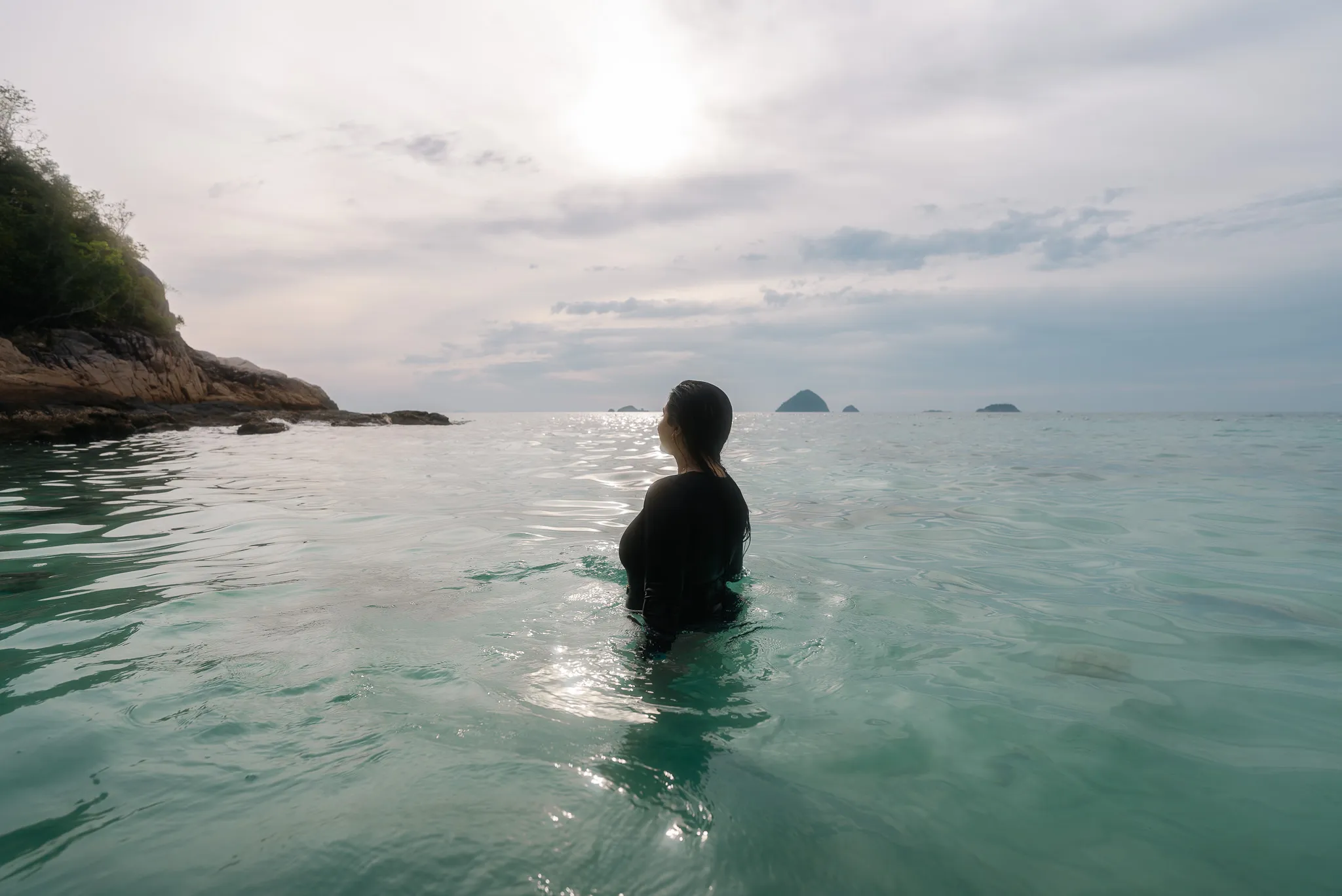 Aroob in the water at Romantic Beach, looking out towards the ocean and distant island.