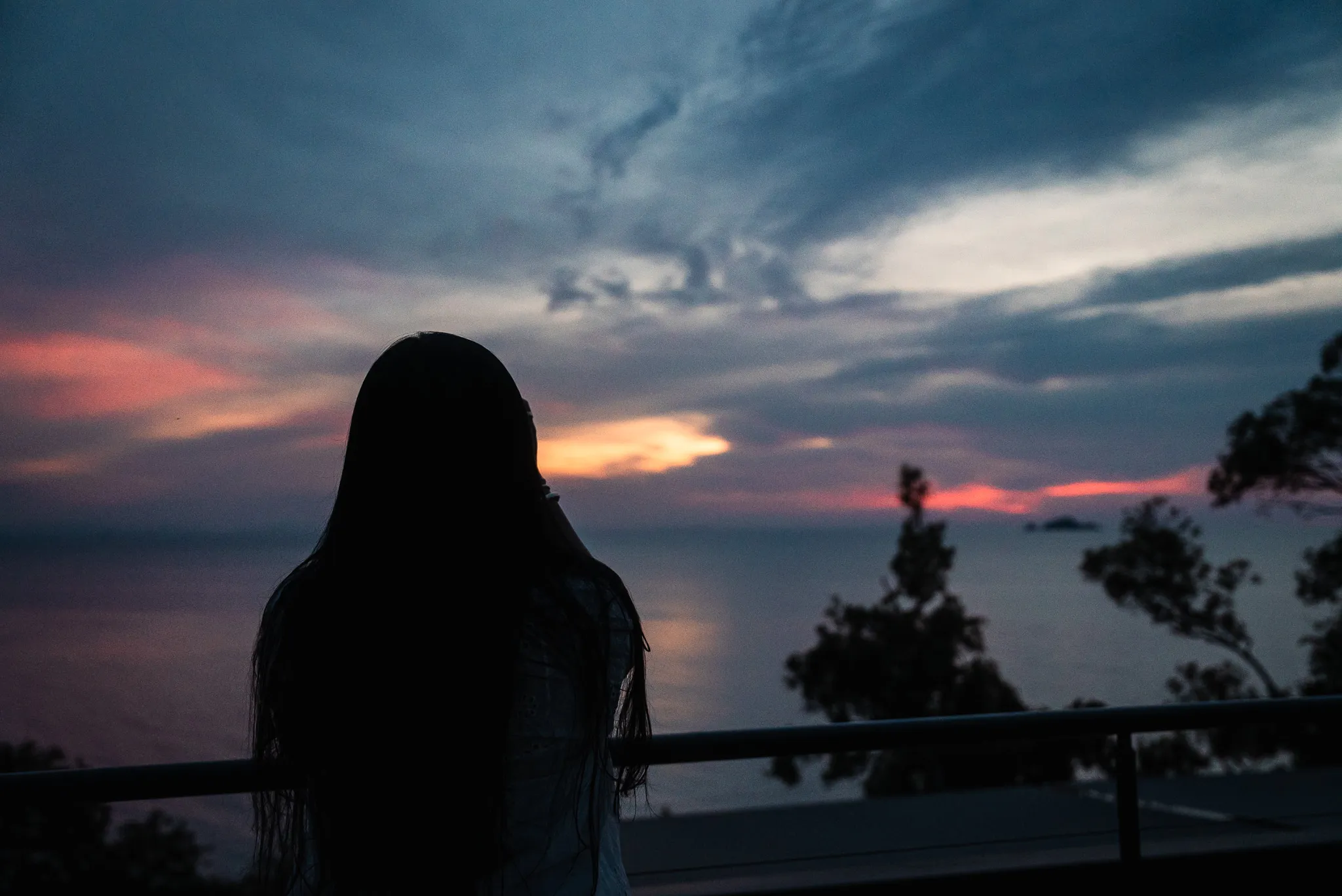 Silhouette of Aroob watching the sunset over the ocean from a viewpoint near an infinity pool