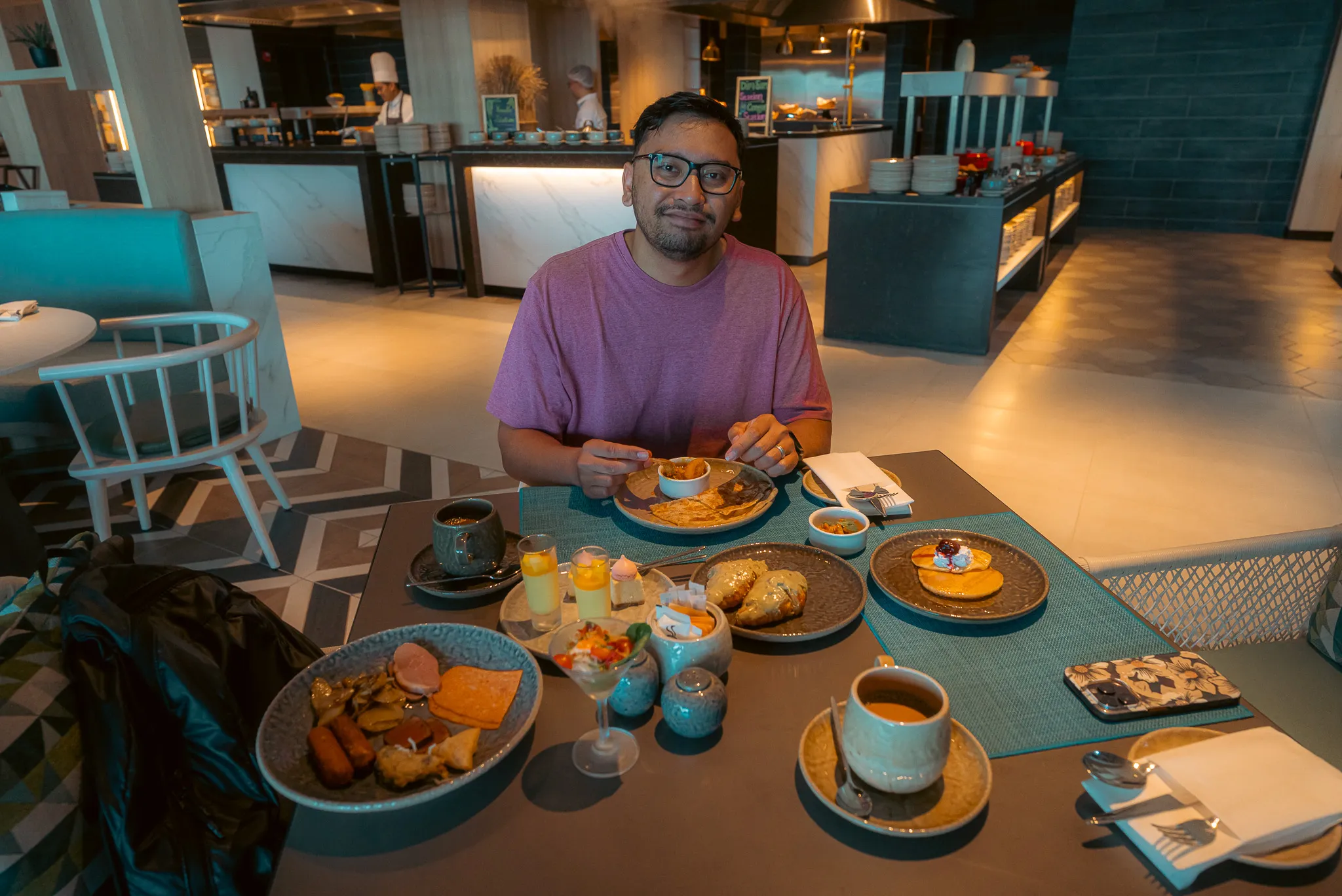 Shariff having breakfast at Dapur restaurant, with a variety of dishes and teh tarik on the table.