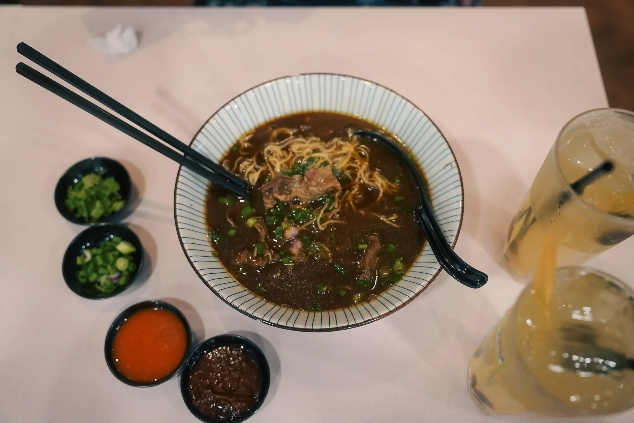 Top view of beef noodles with side sauces at Kim Yong Gee Beef Noodle, Kuala Lumpur